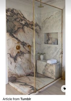 a bathroom with marble walls and flooring, gold fixtures on the shower head stand