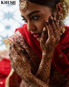 a woman with henna on her hands and face is holding her hand up to her ear