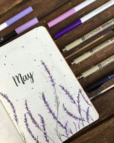 an open notebook with purple flowers and writing on the page next to some pencils