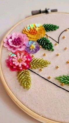 a close up of a embroidery on a hoop with flowers and leaves in the hoop