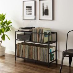 a record player sitting on top of a shelf next to a chair and potted plant