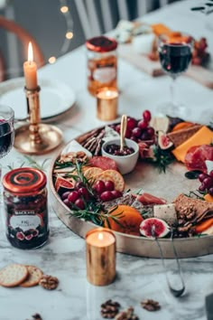 a table topped with lots of food next to a glass of red wine and candles