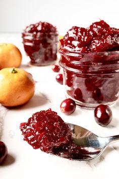 cranberry sauce in a glass jar with spoons and oranges around it