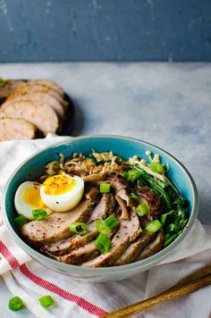 a bowl filled with meat and vegetables on top of a white cloth next to chopsticks