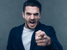 a man in a suit pointing his finger at the camera with an angry look on his face