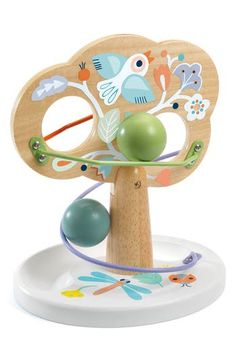 a wooden toy tree with two balls in it and an object on the top one