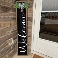 a welcome sign hanging on the side of a brick building next to a door way