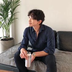 a man sitting on top of a bed next to a plant