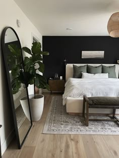 a bedroom with a bed, mirror and plant in the corner on the floor next to it