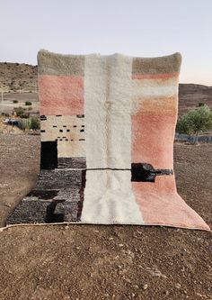 a blanket sitting on top of a dirt ground in the middle of a dry grass field