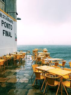 tables and chairs are set up on the side of a building near the ocean with an advertisement for restaurant ponto final