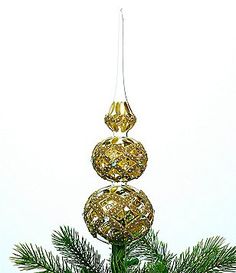 an ornament hanging from the top of a pine tree with three balls on it