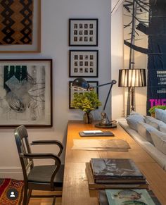 a living room filled with furniture and pictures on the wall next to a table covered in books