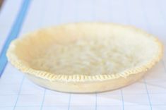 a pie crust in a white bowl on top of a piece of paper with blue lines