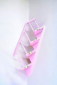 a pink shelf that has three shelves on it and two green dots in the bottom