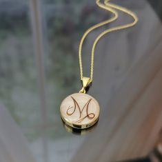 a gold necklace with the letter m engraved on it's front and back sides