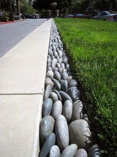 a long line of rocks on the side of a road with grass in the background