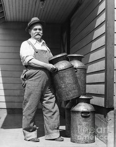 an old black and white photo of a man standing in front of a water tank