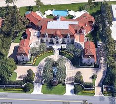 an aerial view of a large mansion surrounded by palm trees