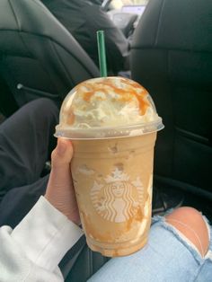 a person holding up a starbucks drink in their hand with caramel and whipped cream on top