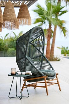 an outdoor lounge chair next to a table with a candle on it