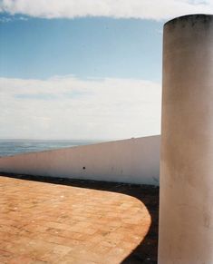 a skateboarder doing a trick in the air near a concrete structure and ocean