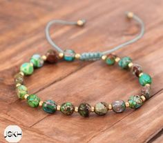 a bracelet with green and gold beads on a wooden surface