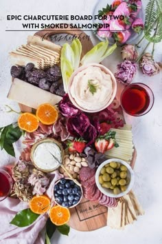 an assortment of cheeses, meats and fruit on a platter with flowers