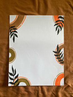 a piece of paper with an orange and black design on it sitting on a bed