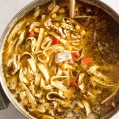 a pot filled with pasta and vegetables on top of a stove next to a wooden spoon