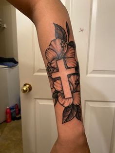 a woman's arm with a cross and flowers on it