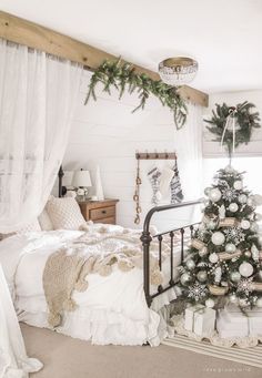 a bedroom decorated for christmas with white and silver decorations on the bed, tree in corner