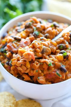 a white bowl filled with beans and tortilla chips on top of a table