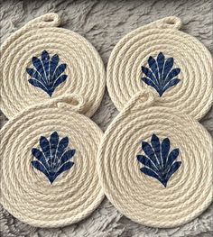 four coasters with blue leaves on them sitting on a white rug in front of a wall