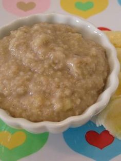 a bowl filled with oatmeal next to sliced bananas on a colorful tablecloth