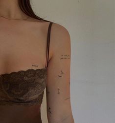 a woman wearing a bra with birds on her arm and writing on the side of her chest