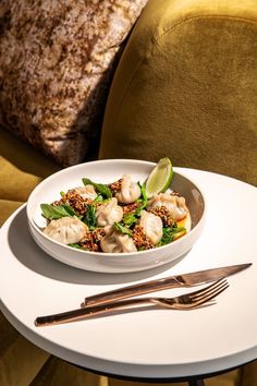 a white plate topped with dumplings and broccoli on top of a table