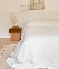 a white bed sitting in a bedroom next to a wooden table