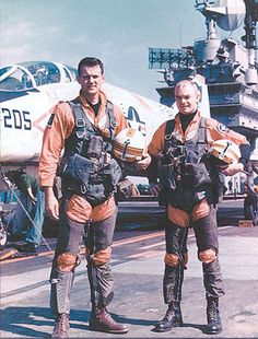 two men standing next to each other in front of an airplane