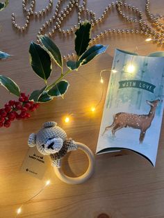 an open book with a deer on it next to some christmas lights and a teddy bear