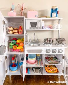 a play kitchen with lots of toys and food on the shelves in front of it