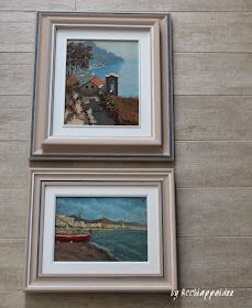 two framed paintings on the wall next to each other, one has a boat in it