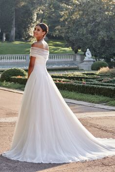 a woman in a white wedding dress posing for the camera with her hand on her hip