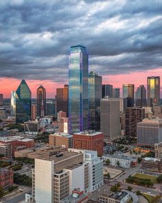 an aerial view of a city with tall buildings in the foreground and clouds in the background