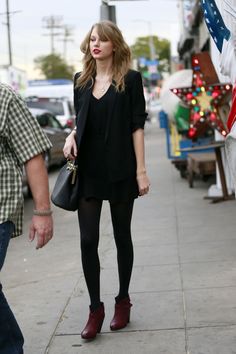 a woman walking down the street with a handbag on her hip and another man standing next to her