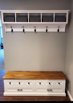 a white bench sitting under a coat rack with hooks on it's back end