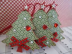 two green christmas trees with red bows on top of sheet music paper and white stars