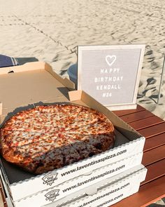 a large pizza sitting on top of a wooden table next to two boxes of pizza