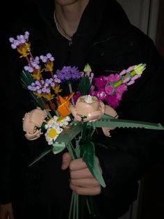 a person holding a bouquet of flowers in their hands and wearing a black hoodie