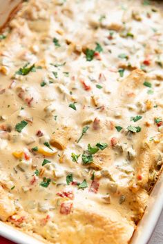 a casserole dish filled with chicken, cheese and vegetables on a red cloth